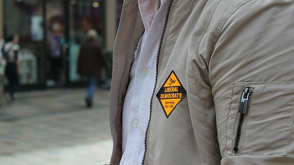 A person's jacket displaying a Liberal Democrat sticker